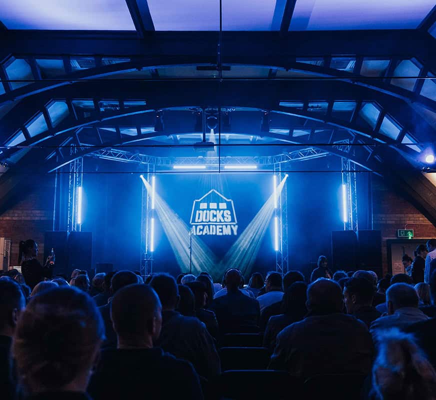 Docks Academy Nominated for ‘Accessible & Inclusive Tourism’ Award! Photograph of a venue from the back with people sat down for a comedy event